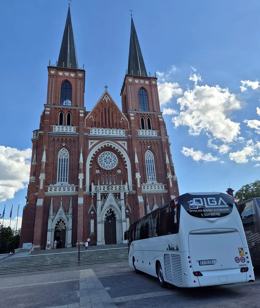 Autokar Iveco Magelys z logo OLGA przed archikatedrą w Częstochowie